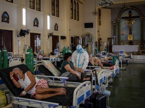 A health worker in PPE [personal protective equipment] ministers to patients in the chapel of Quezon City General Hospital, which has been turned into a Covid-19 ward amid rising Delta variant infections in the Philippines. Questions have been raised concerning overpriced medical gear and equipment p urchased by the Philippine government. Photo: CNS/Eloisa Lopez, Reuters