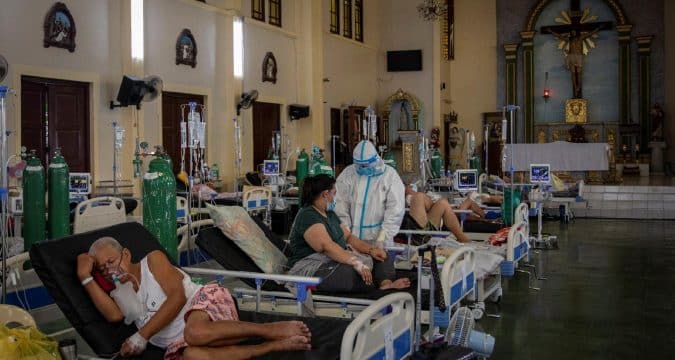 A health worker in PPE [personal protective equipment] ministers to patients in the chapel of Quezon City General Hospital, which has been turned into a Covid-19 ward amid rising Delta variant infections in the Philippines. Questions have been raised concerning overpriced medical gear and equipment p urchased by the Philippine government. Photo: CNS/Eloisa Lopez, Reuters