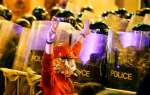 An anti-government protester in Beirut passing in front of riot police on December 15. Photo: CNS/Reuters