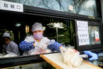 A server wearing a protective mask delivers buns to a customer through a ramp from a restaurant counter at a store in Beijing on February 12. Photo: CNS/Reuters