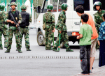 Two Uyghur boys watch Chinese soldiers standing guard at a roadblock in the city of Urumqi, Xinjiang, in 2019. File photo: CNS/Reuters