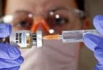 A woman holds a small bottle labeled with a "Vaccine COVID-19" sticker and a medical syringe in this photo illustration. (CNS Illustration/Dado Ruvic, Reuters)