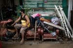 A man sits on furniture covered in mud in Batangas, the Philippines, on November 2 following floods caused by Super Typhoon Goni. Photo: CNS/Reuters
