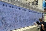 People write the names of loved ones on a newly created memorial wall outside Quiapo Church. Photo: UCAN/courtesy of Father Douglas Badong via Radio Veritas