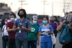 Workers in protective gear wait for shuttle services in Manila, the Philippines. Photo: CNS/Eloisa Lopez, Reuters