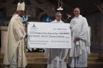 Monsignor Chauvet, centre, receiving a check from Monsignor Rossi and Cardinal Gregory after a special Mass on September 16. Photo: CNS/Tyler Orsburn