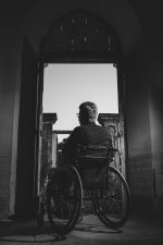 grayscale photography of man sitting on wheelchair