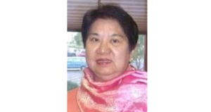Portrait of an Asian woman wearing a pink scarf, looking at the camera.