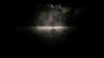 Night scene of a foggy lake with a line of leafless trees reflected on the water, in darkness.