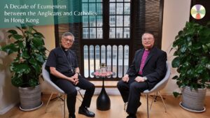 Two clergy members sit in chairs with a round table between them, inside a bright room with plants and a window behind; overlay text about ecumenism between Anglicans and Catholics in Hong Kong.