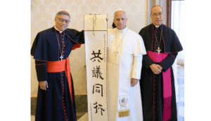 Three clergy members stand together, presenting a tall scroll with East Asian calligraphy.