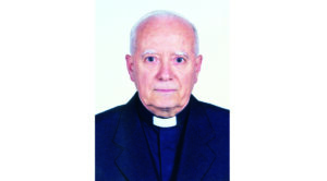 Portrait of an elderly man in a clerical black suit with a white collar facing the camera, neutral expression.