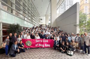 Large group of people posing outdoors behind a pink banner that reads Serra Club of Hong Kong.