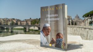 Book cover shows Pope Francis with a baby, title Disarmata e disarmante, set against a Roman river backdrop.